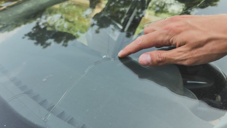 Male hand pointing out cracked windshield
