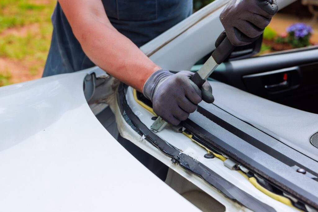 Man replacing rubber that holds windshield