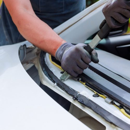Man replacing rubber that holds windshield